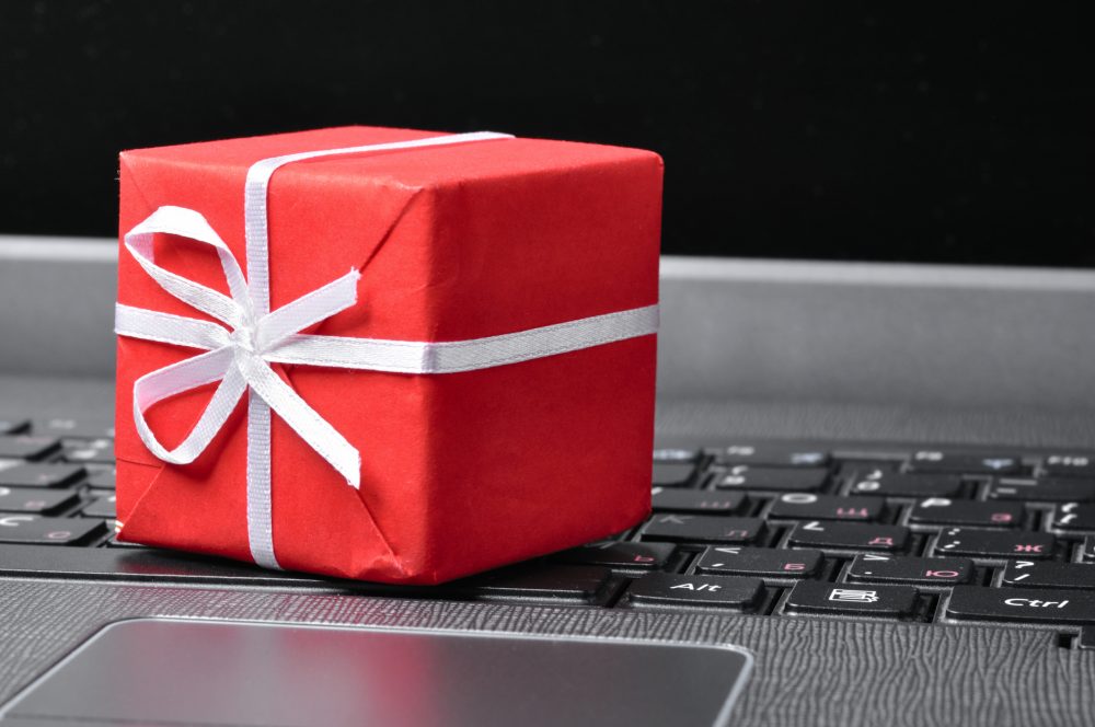 red gift box on a white laptop. tech christmas gifts